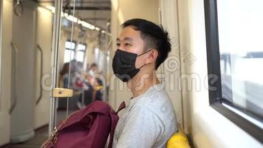 在地铁列车上，一名戴着黑色手术面罩的亚洲年轻人在新型冠状病毒Covid19号列车上关门